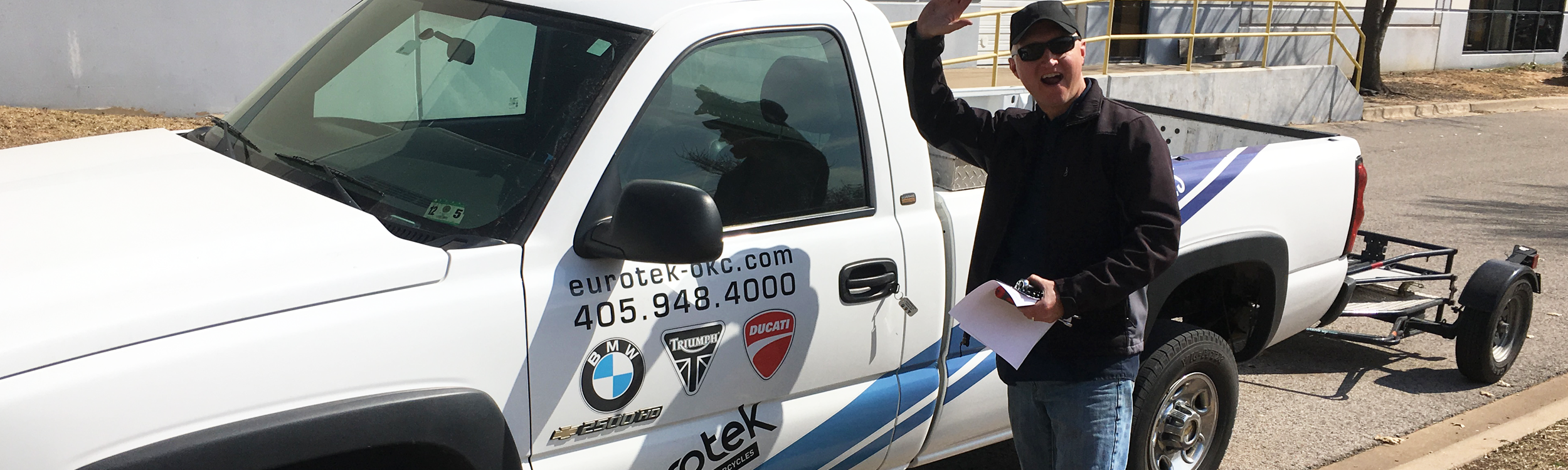 Eurotek OKC Employee waving in front of truck.