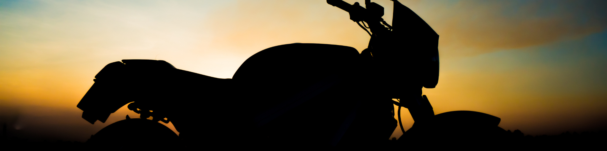Silhouette of a motorcycle at sunset, symbolizing freedom and the open road