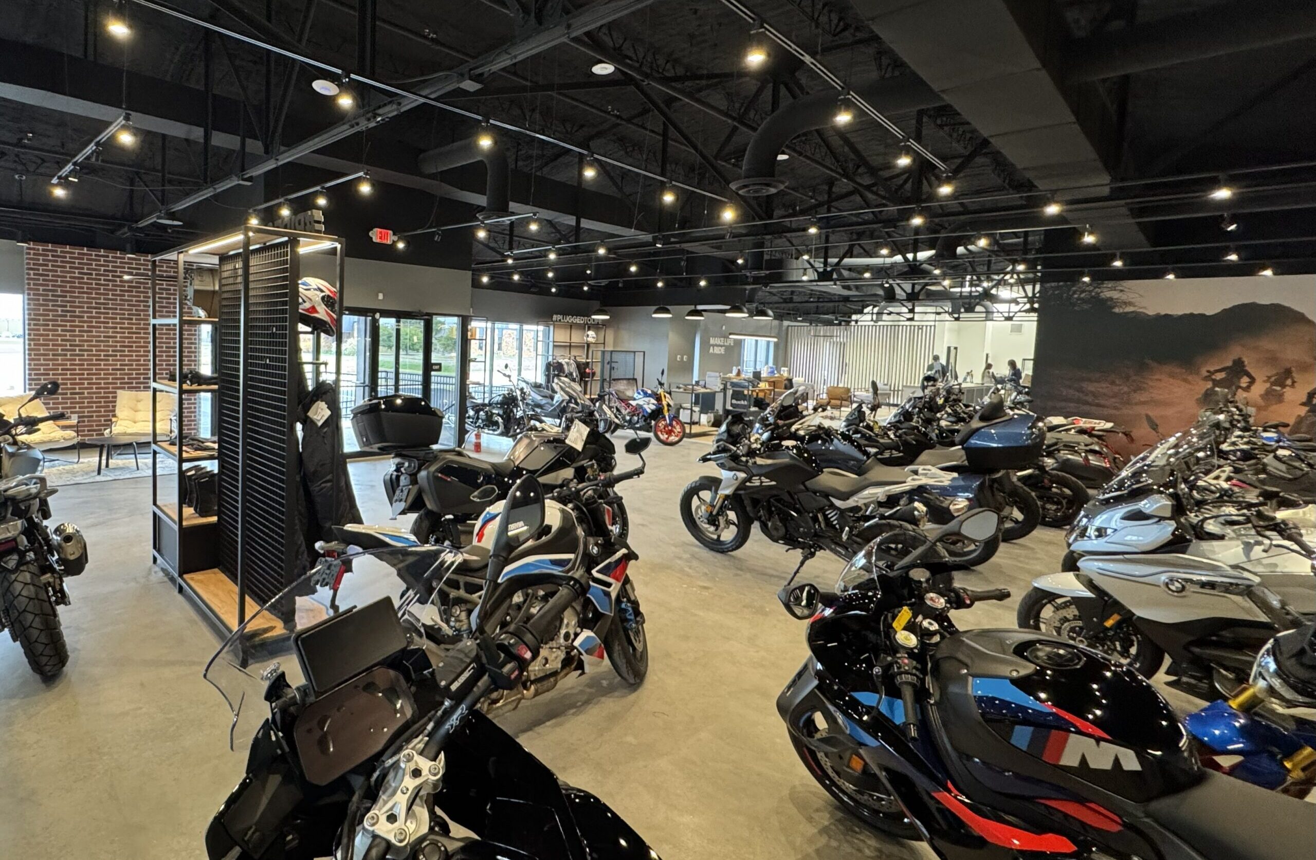 Wide view of the Eurotek OKC motorcycle showroom displaying multiple BMW motorcycles, including adventure and sport models, arranged under modern industrial lighting in the new dealership location.