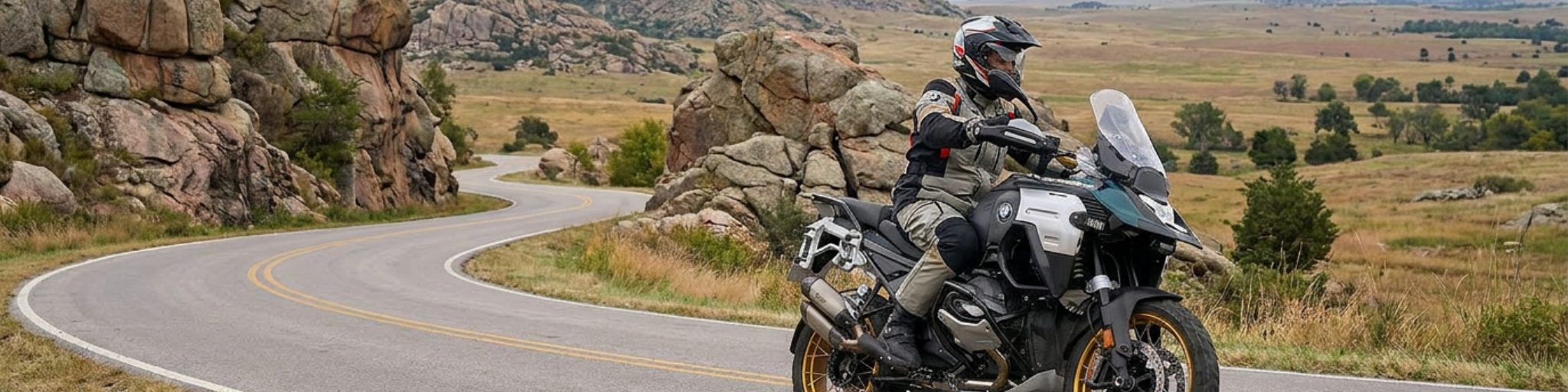 Motorcycle rider on a winding road through the Wichita Mountains Wildlife Refuge near Lawton, Oklahoma, with granite rock formations and open prairie in the background.